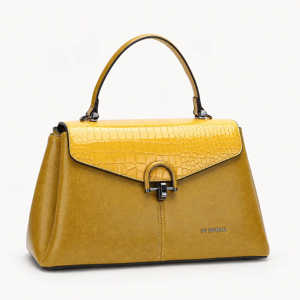 SU QUEENA 3016 mustard bag with yellow embossed flap and dark horseshoe closure, isolated on off-white.